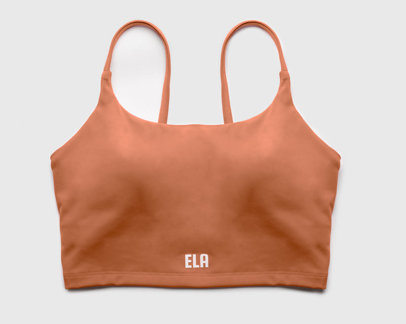 Flatlay of a beige sports bra with shoulder straps and built-in bra pads