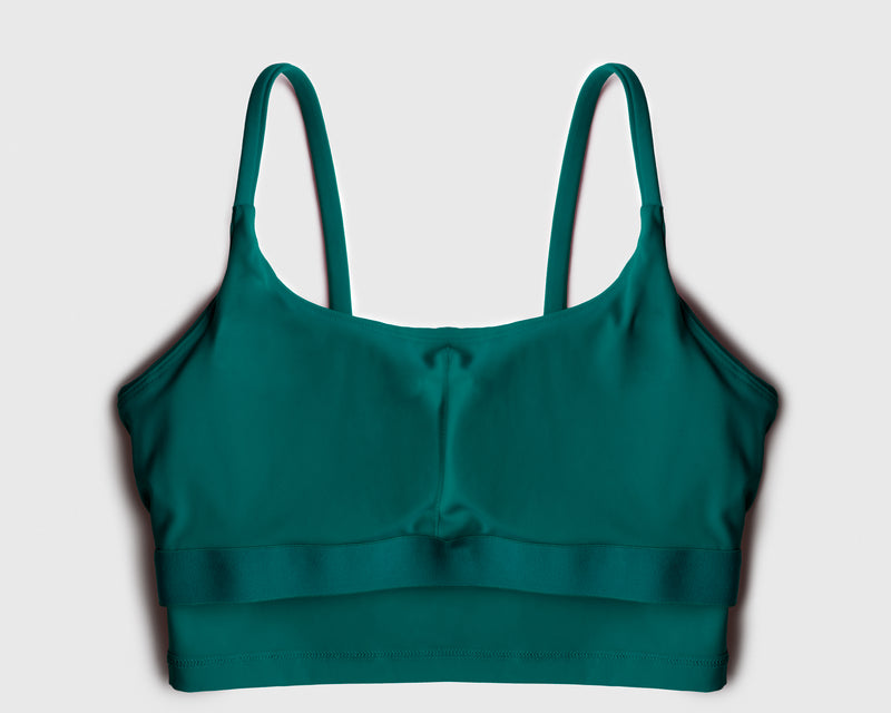 Flatlay of a teal green sports bra showing internal structure of built-in bra pads 