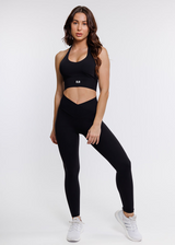 female model in black halter neck sports bra with matching leggings suitable for variety of athletic activities, gym, yoga and workout.
