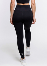 A female model showing the back of the ButterBod Hourglass Leggings. The high-waisted wrap design and V-cut waistband accentuate her curves, while the booty-lifting back seam provides a flattering lift. The leggings have a soft matte finish, medium compression, and are made from 4-way stretch fabric for maximum comfort and versatility.