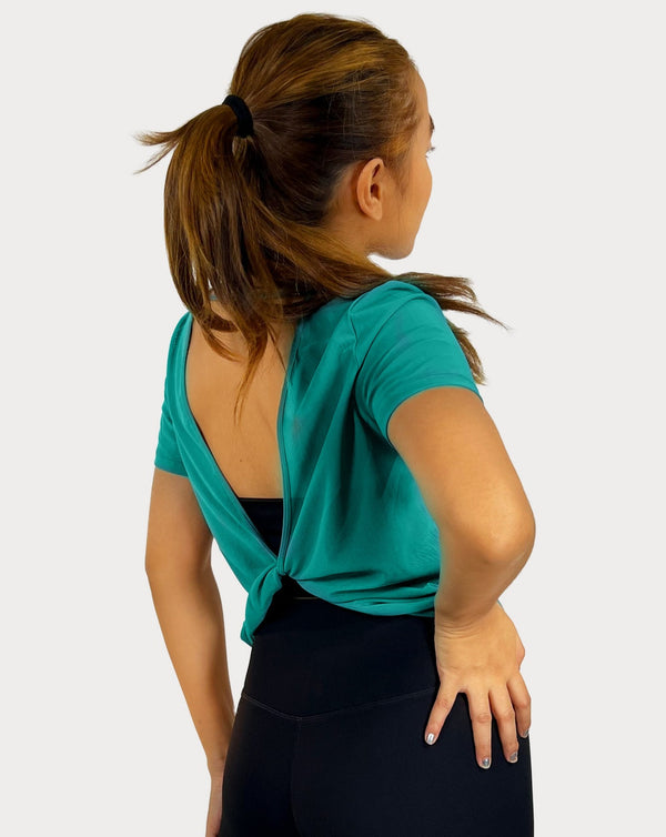 Female model is showing the green gym tee that has a round scoop neck in the front made of fine mesh fabric with a flattering V-shaped twisted open back design. The top is perfect for use as a cover-up on top of a sports bra and is great for gym, yoga, or everyday wear. 