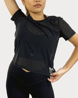 Female model is showing the black gym tee that has a round scoop neck in the front made of fine mesh fabric with a flattering V-shaped twisted open back design. The top is perfect for use as a cover-up on top of a sports bra and is great for gym, yoga, or everyday wear. 